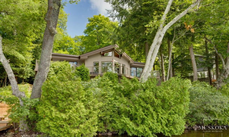 House surrounded by trees and greenery with 'Muskoka' branding.