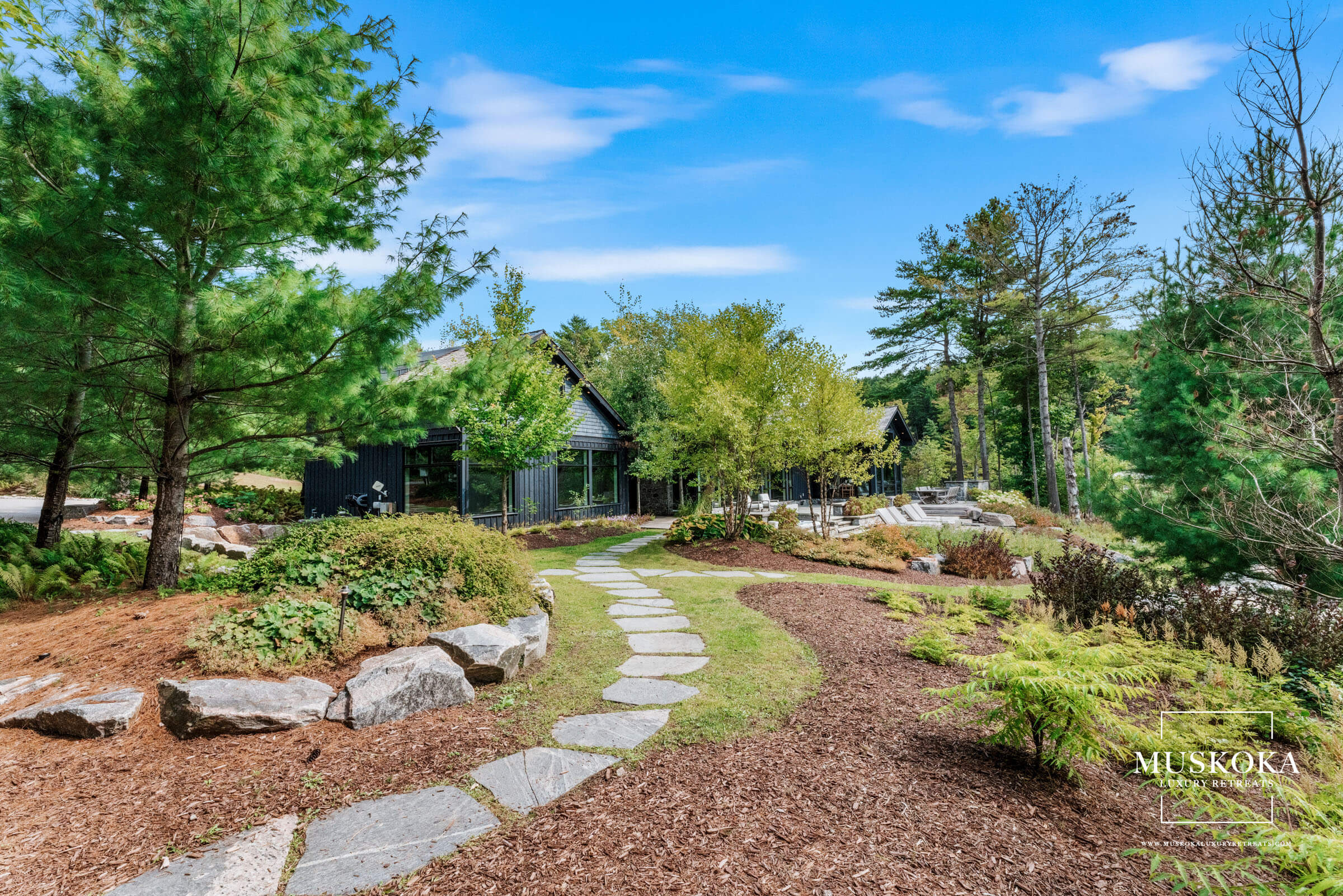 Scenic garden with stone pathway, trees, and clear blue sky