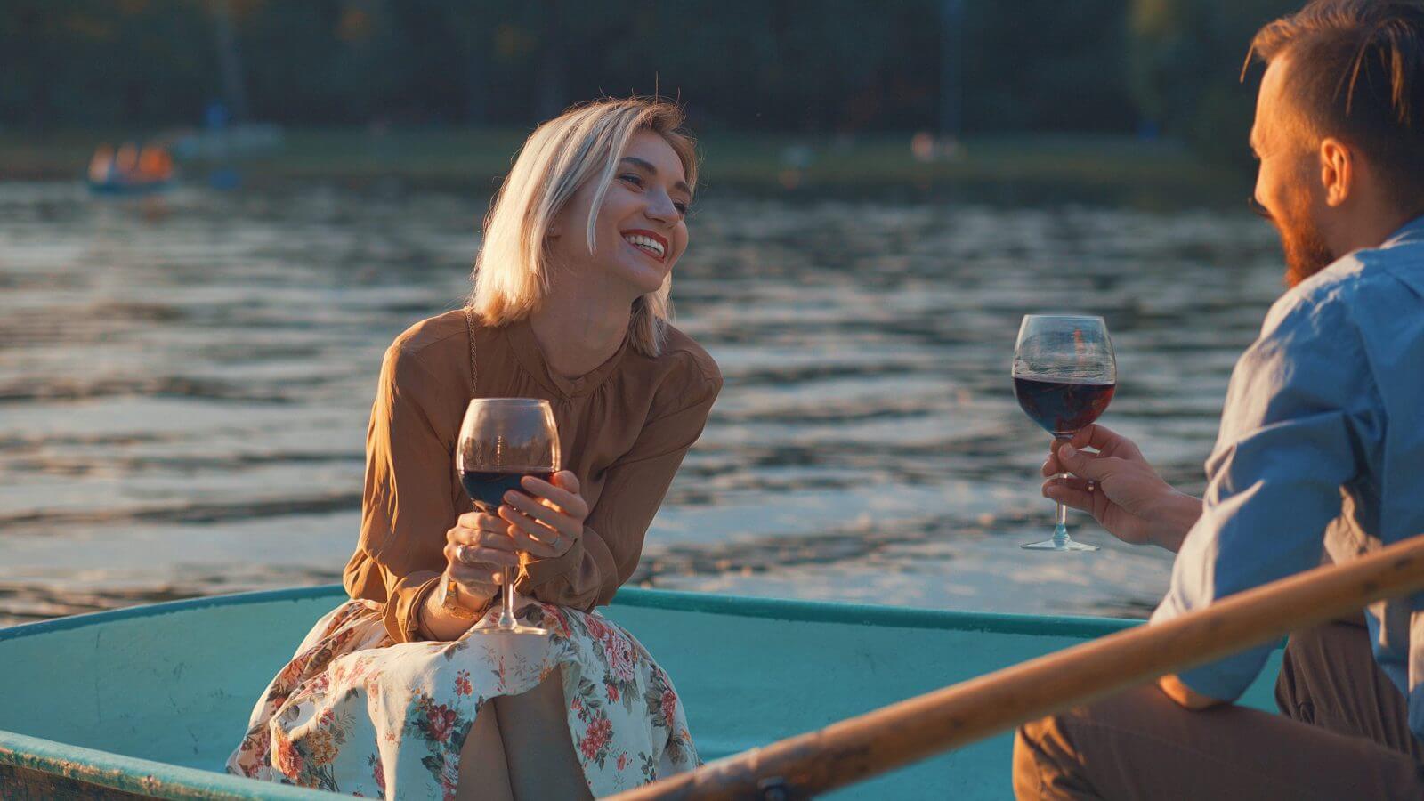 Two people in a boat on a lake, enjoying wine and each other's company.