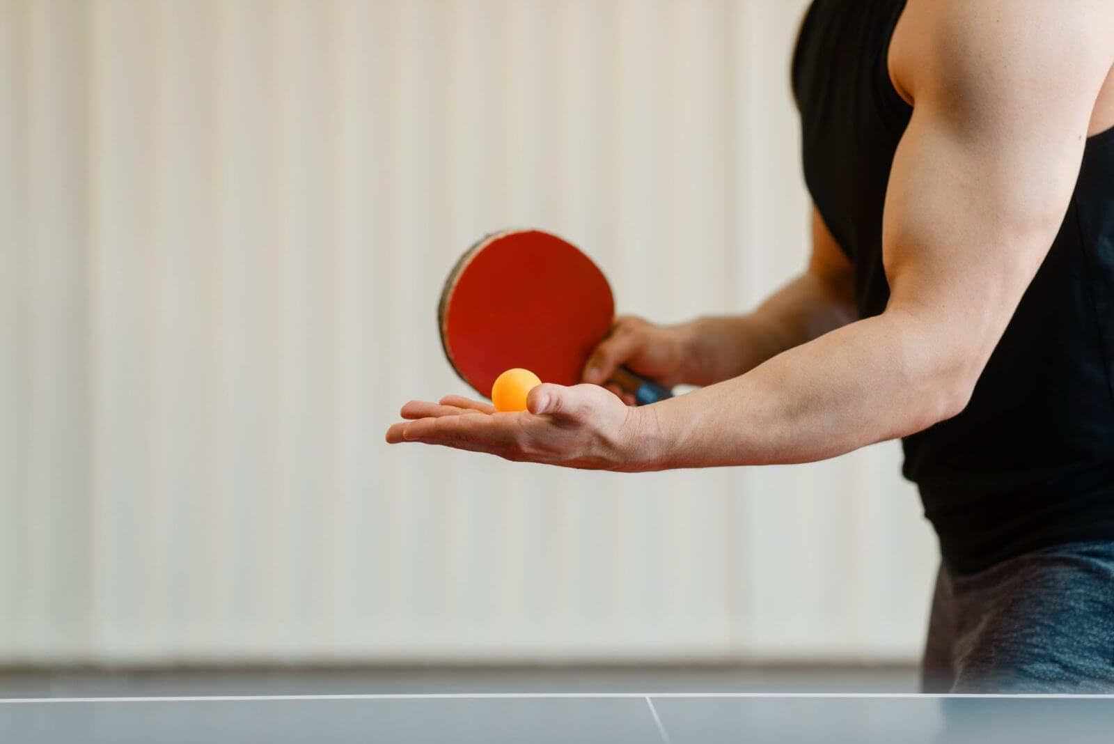 Person holding a ping pong ball and paddle