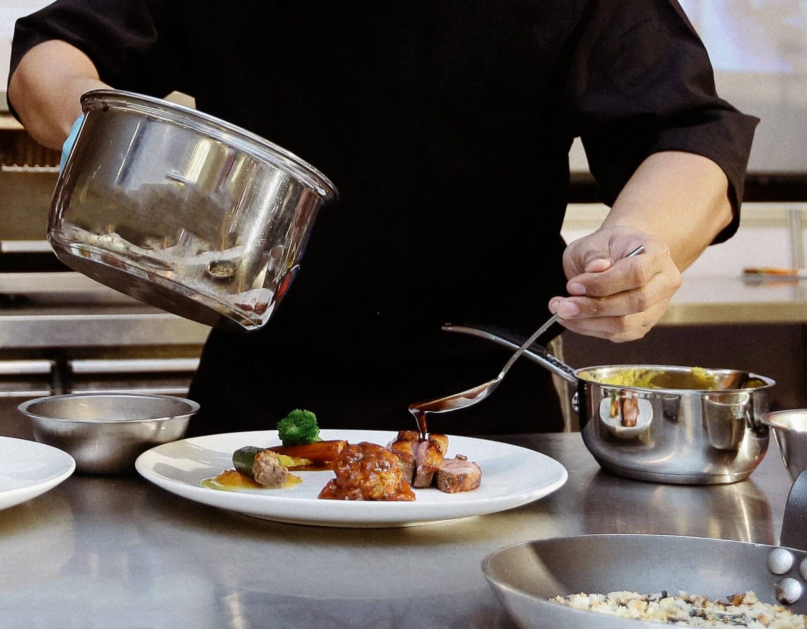 Chef plating food in a professional kitchen setting
