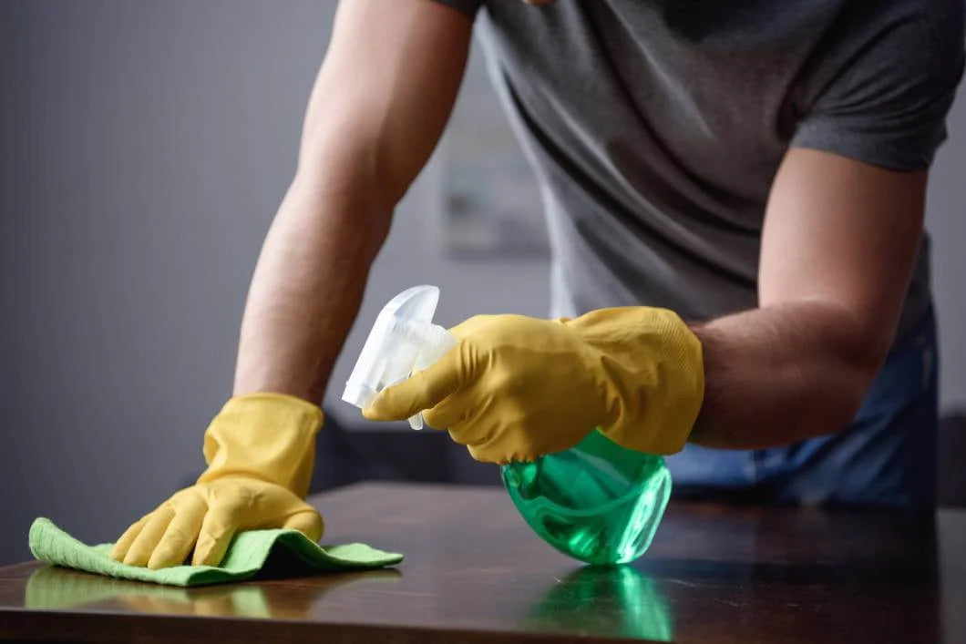 Person cleaning a surface with gloves and cleaning supplies