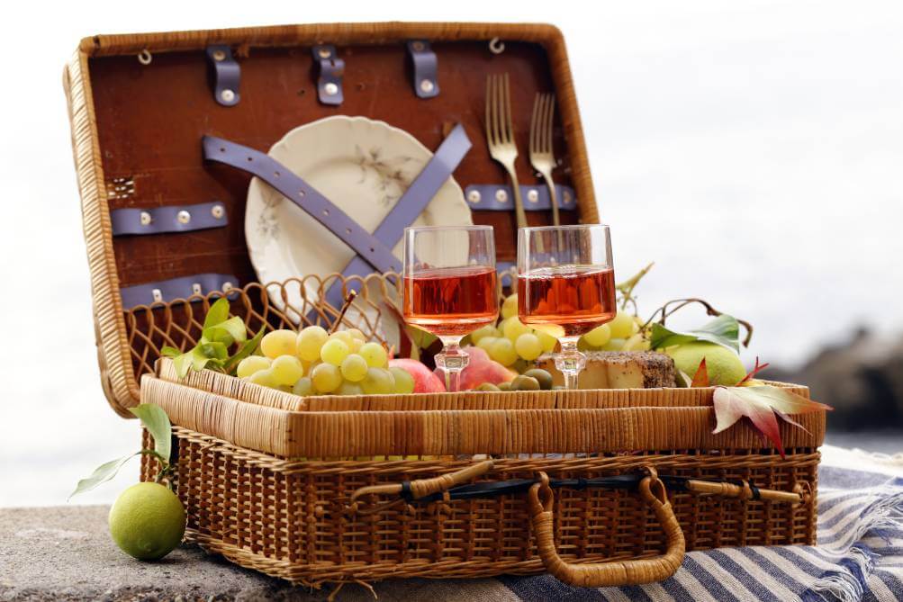 Open picnic basket with food and drinks on a table