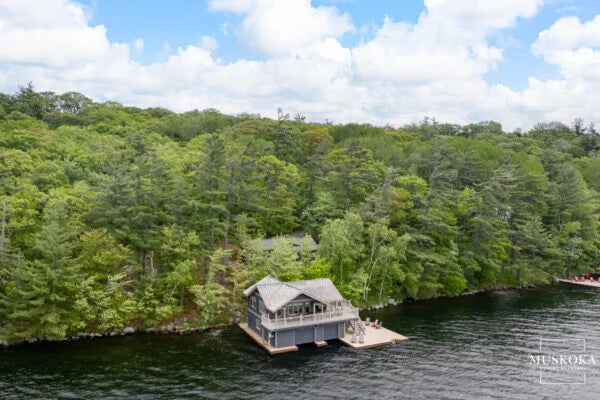 Boathouse on a lake surrounded by trees with a clear blue sky.
