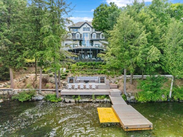Lake house with a dock and chairs surrounded by trees